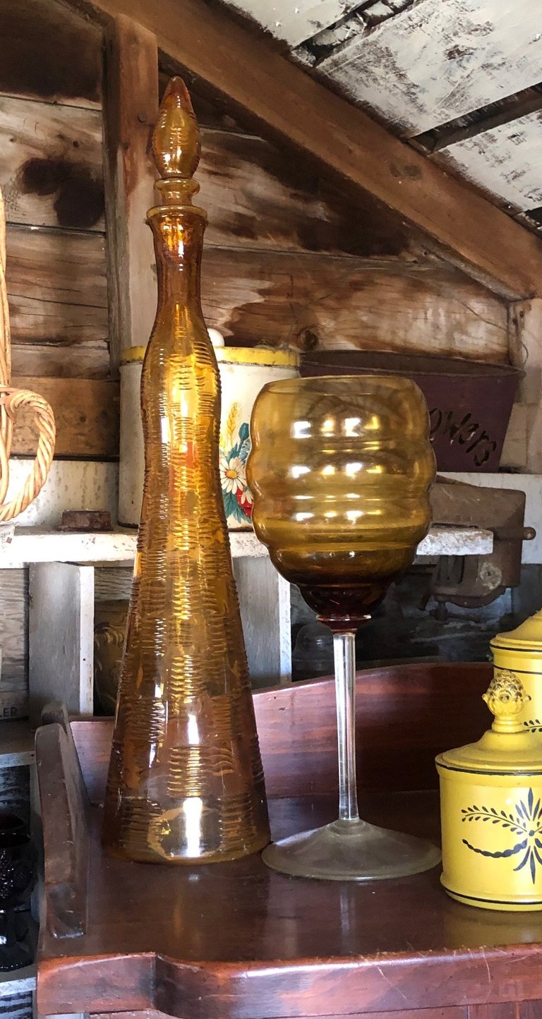 Two amber glass decorative bottles on a wooden shelf in a rustic interior setting