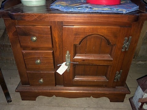 Vintage wooden cabinet with three drawers on left side, arched door compartment on right, and decorative base trim