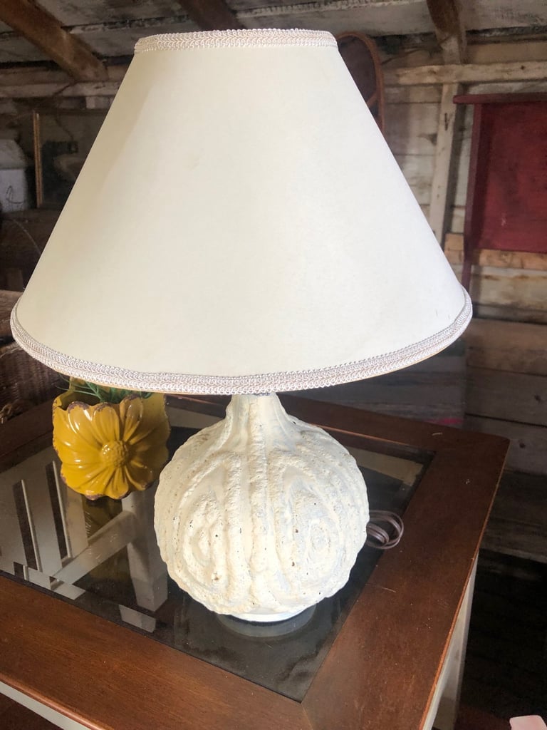 White ceramic table lamp with textured spherical base and cream-colored linen shade on wooden surface