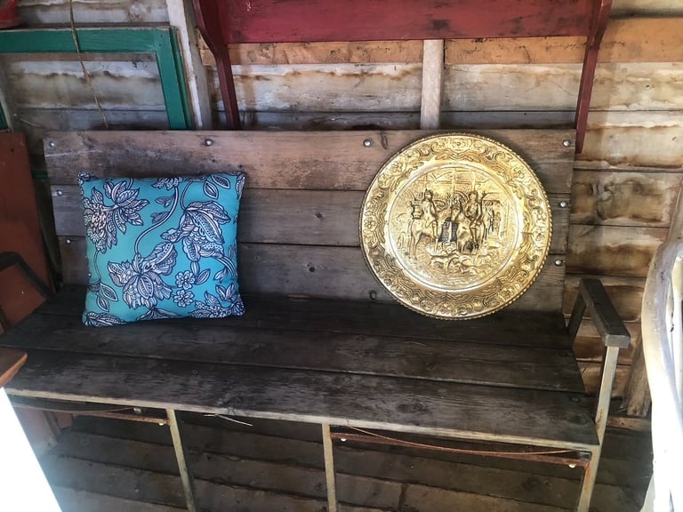 A wooden bench displaying a decorative blue patterned cushion and a gold ornamental plate
