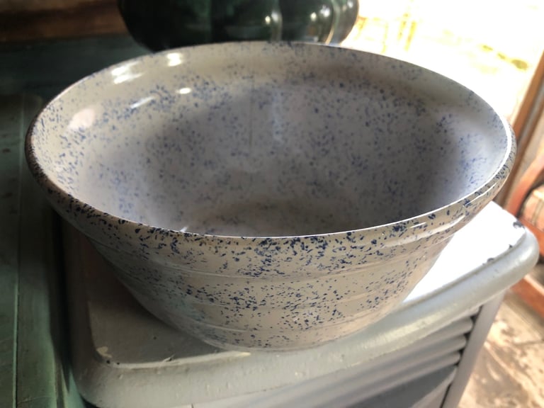Empty ceramic bowl with speckled grey and white glaze sitting on a shelf